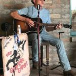 Architect Brian Curley sitting down and playing the guitar